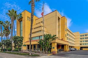 A hotel with a yellow facade, multiple floors, and a flagpole. - Holiday Inn Express & Suites Anaheim Convention Center Area by IHG (Anaheim)