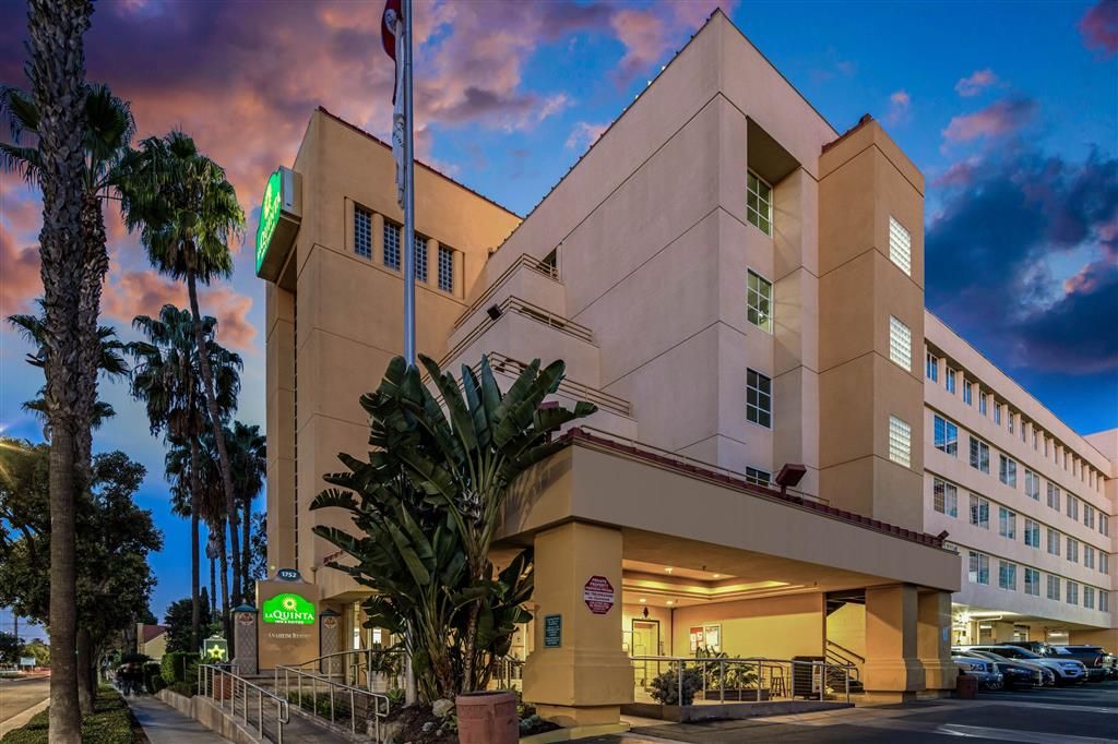 A hotel with a modern architectural design, featuring a prominent entrance and a parking area.