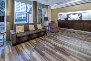A modern lobby with a sofa, a small table, and a reception desk. - Holiday Inn Express & Suites Anaheim Convention Center Area by IHG (Anaheim)