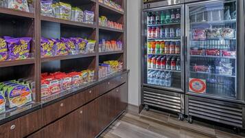 A snack and beverage vending area with multiple shelves stocked with various snacks and a refrigerator with beverages.