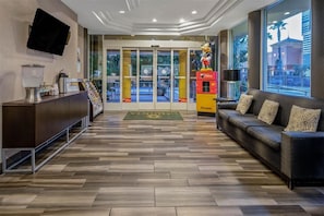 A hotel lobby with a reception desk, a sofa, a large window, and a Mickey Mouse statue. - Holiday Inn Express & Suites Anaheim Convention Center Area by IHG (Anaheim)