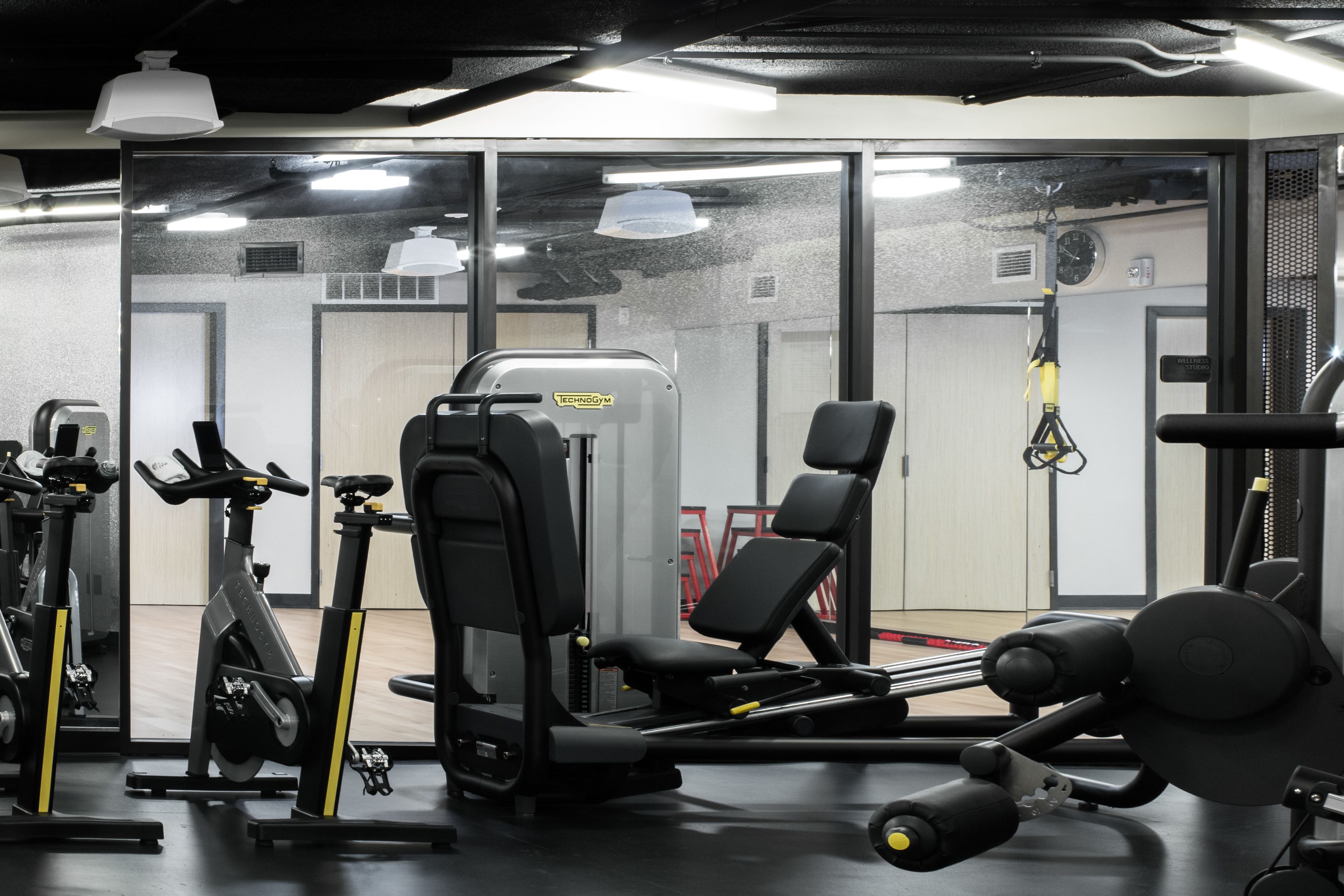 A gym with exercise equipment, a mirror, and a door leading to another room.