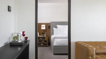A hotel room with a bed, bedside table, and a brown leather sofa.