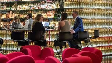 A bar with multiple shelves of liquor bottles, bar stools, and a counter with a computer.