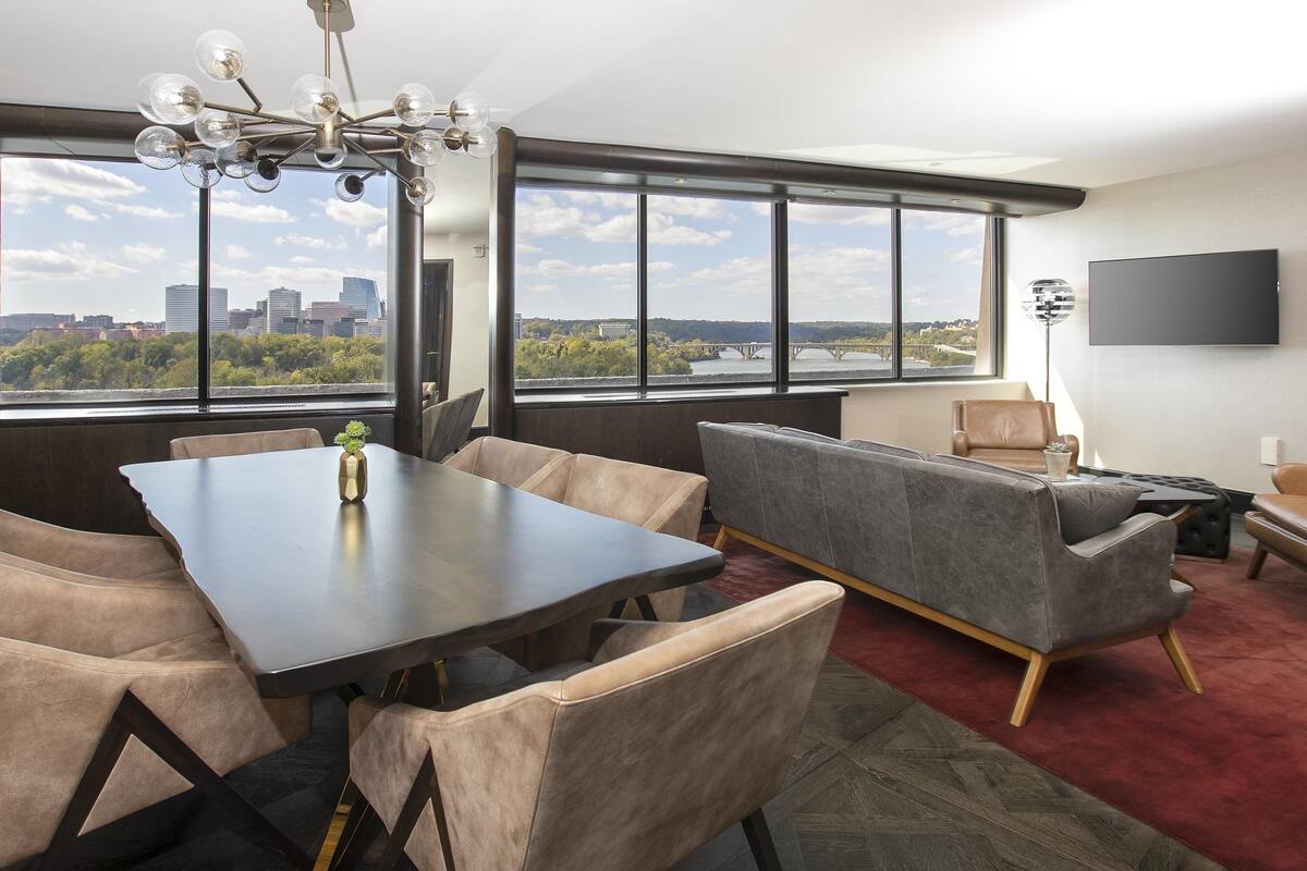 Une pièce moderne comprenant une table à manger, des chaises, un canapé et un téléviseur.