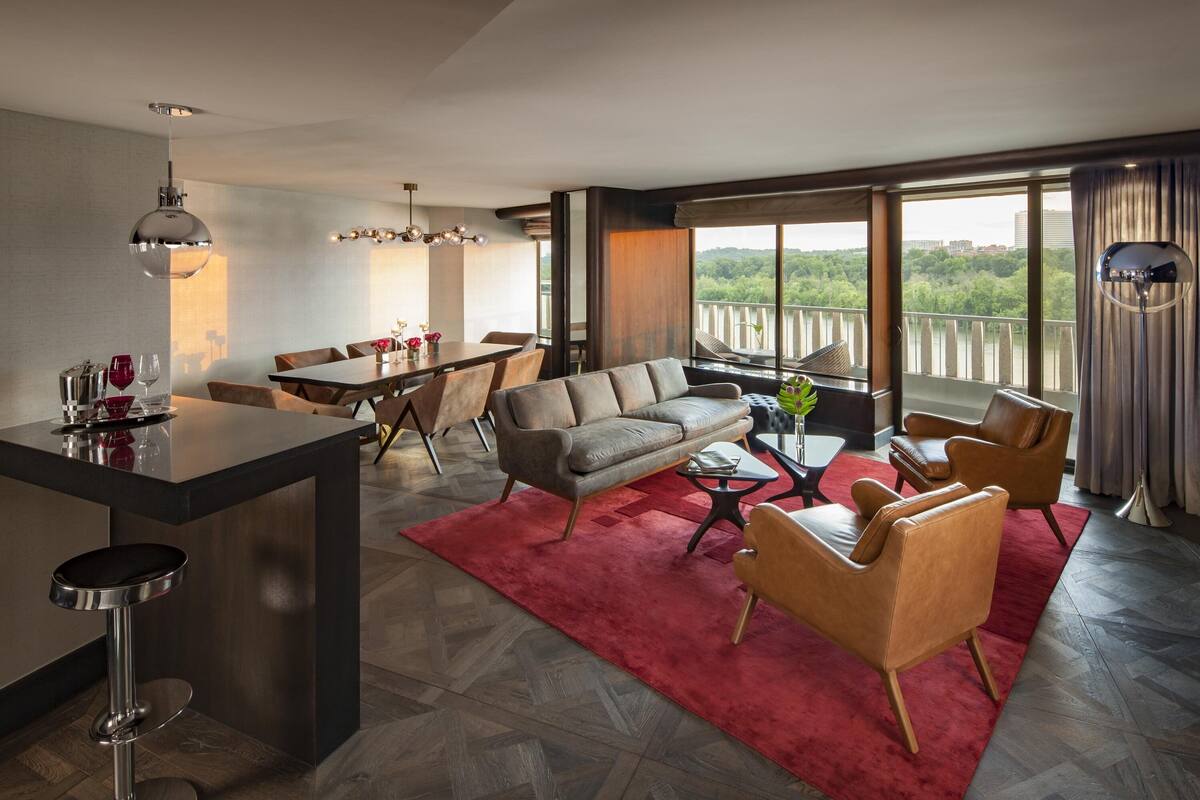 Un salon moderne comprenant un canapé, des fauteuils, une table à manger et un coin cuisine.