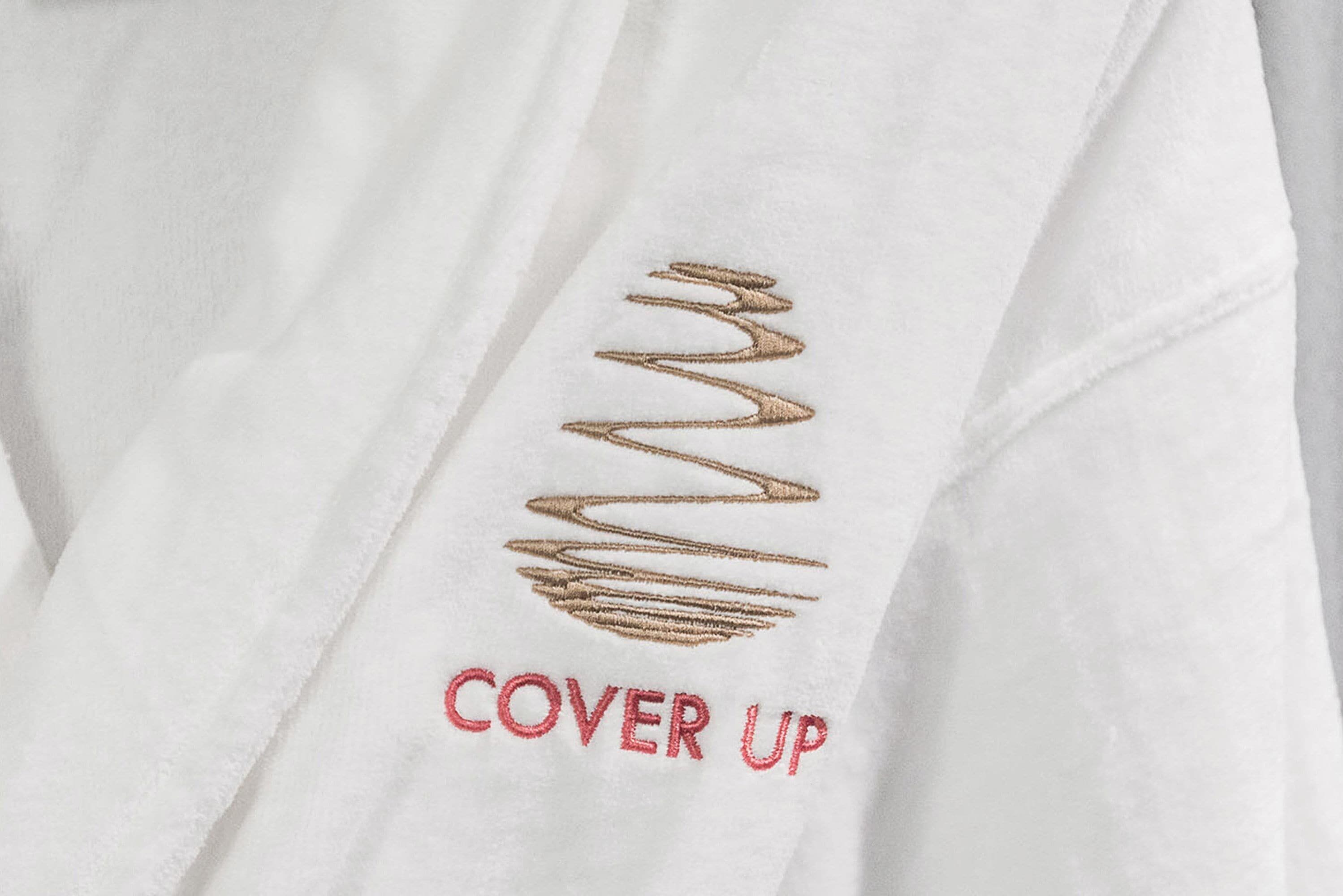 A white garment with a gold embroidered design and the text "COVER UP" in red.