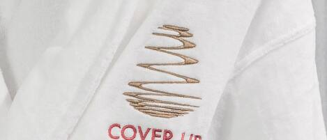 A white garment with a gold embroidered design and the text "COVER UP" in red.