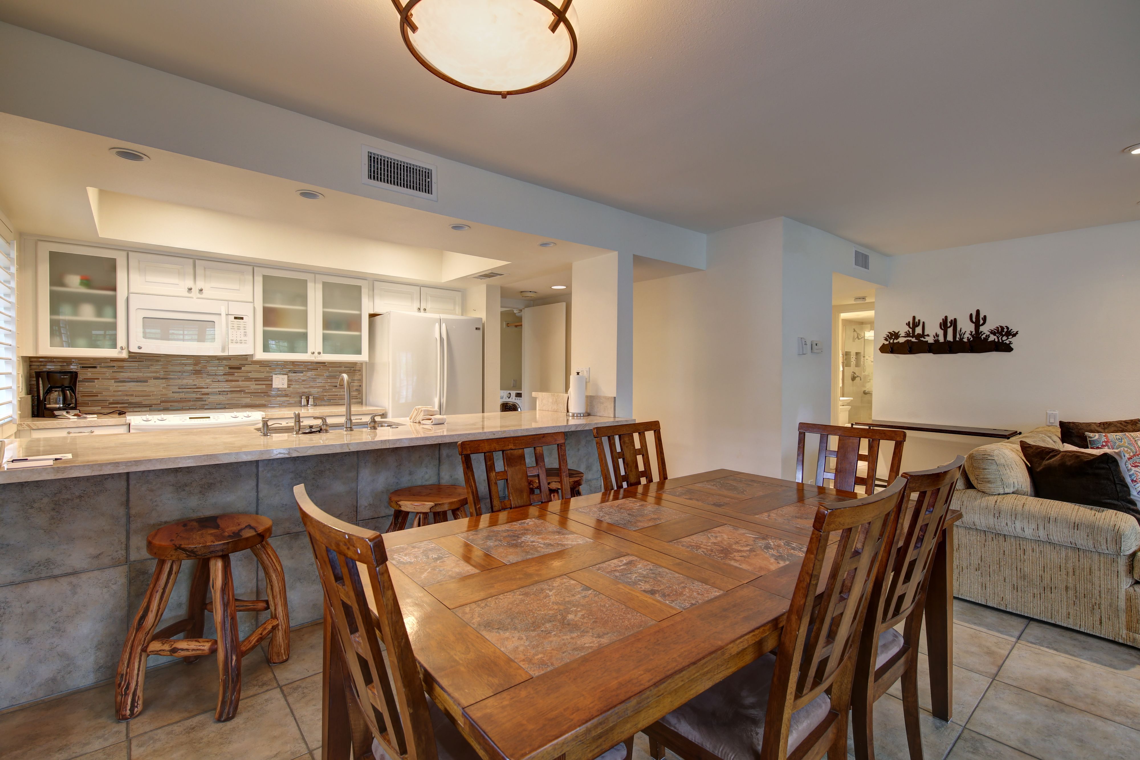 A modern kitchen with a central island, wooden chairs, and a dining table.