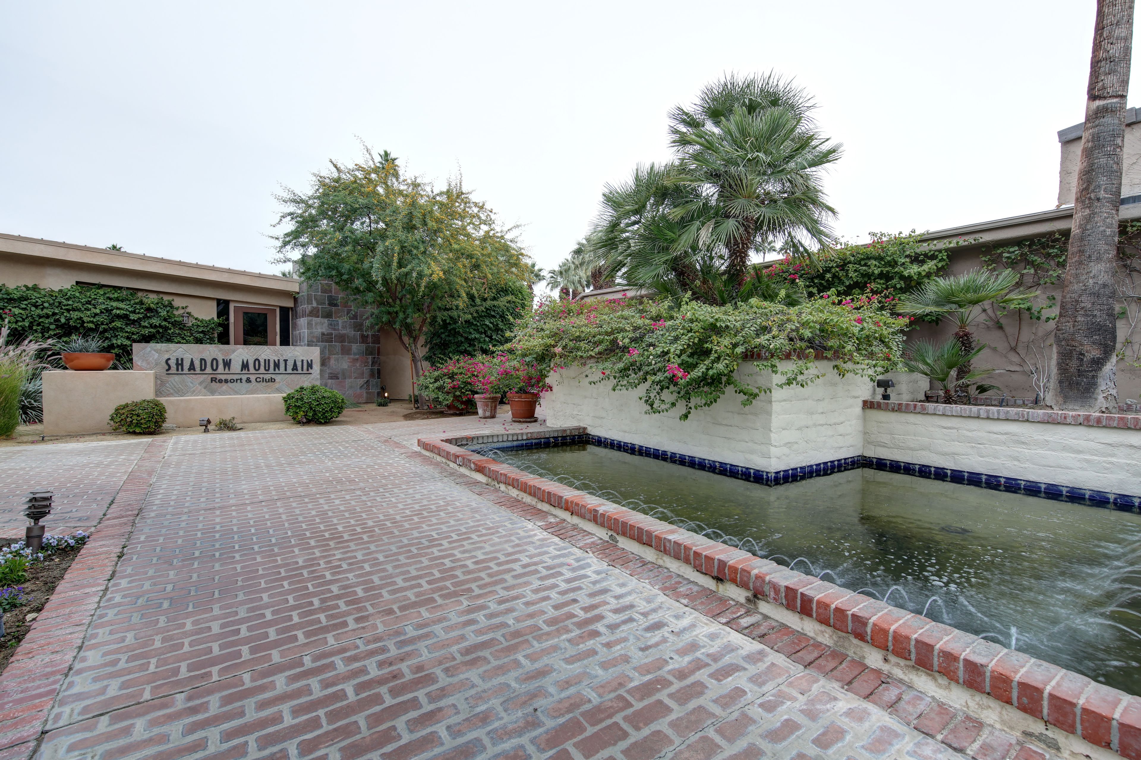 A brick pathway leading to a pool with a sign for Shadow Mountain Resort & Club.