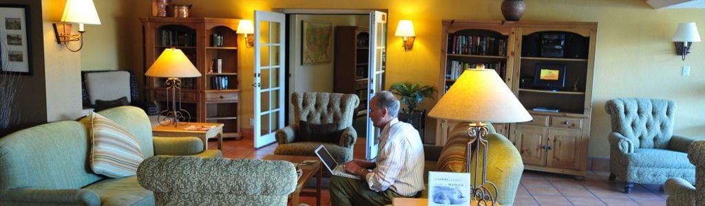 Un salon chaleureux avec un canapé, des fauteuils, une table basse et une cheminée. On y trouve également une bibliothèque remplie de livres et un téléviseur.