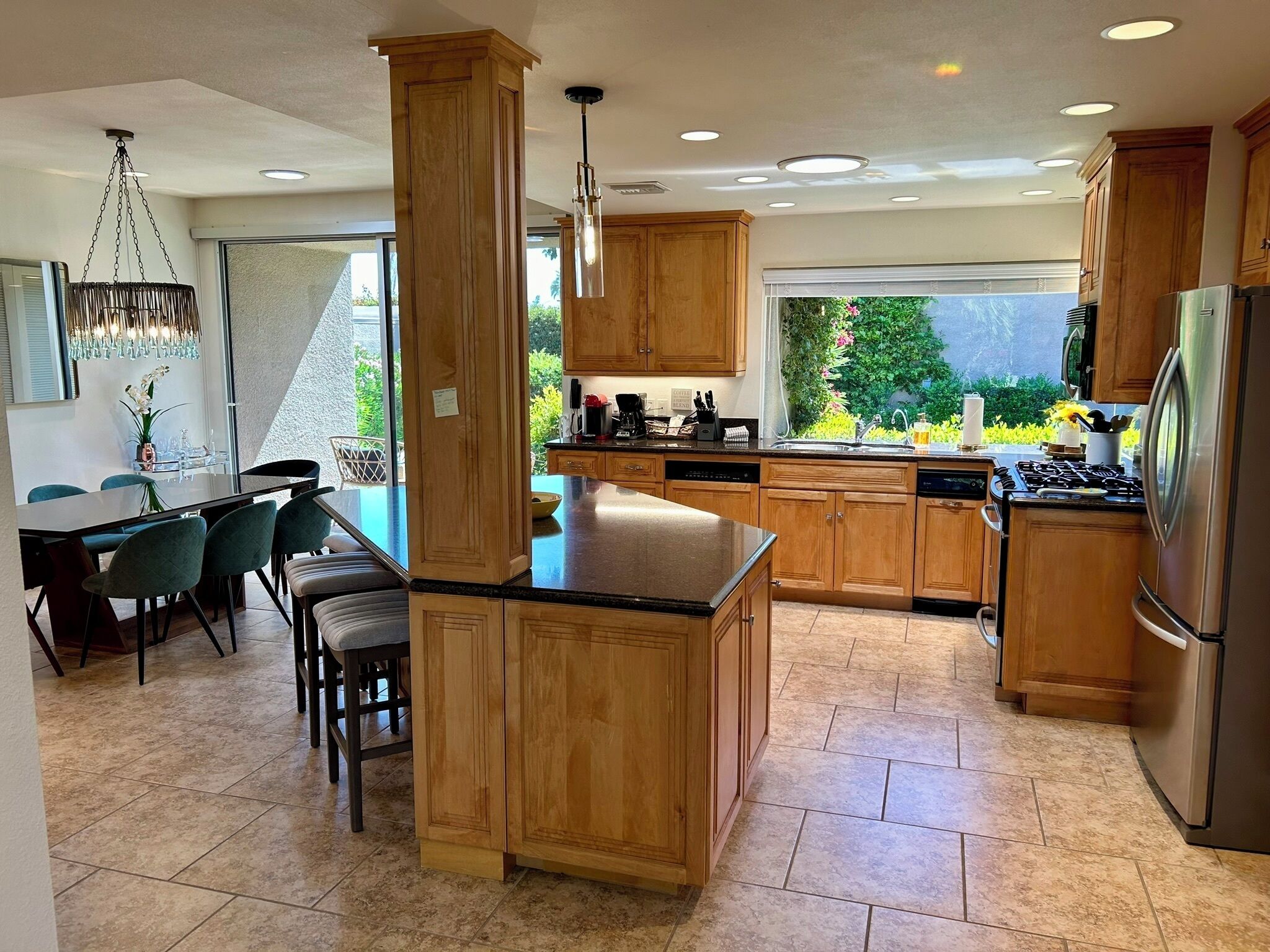 A modern kitchen with wooden cabinets, a central island, and a dining area with chairs.