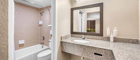 Une salle de bain avec une baignoire, des toilettes et un lavabo, avec un miroir au-dessus du lavabo.