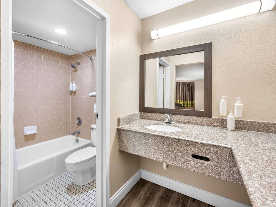 Une salle de bain avec une baignoire, des toilettes et un lavabo, avec un miroir au-dessus du lavabo.