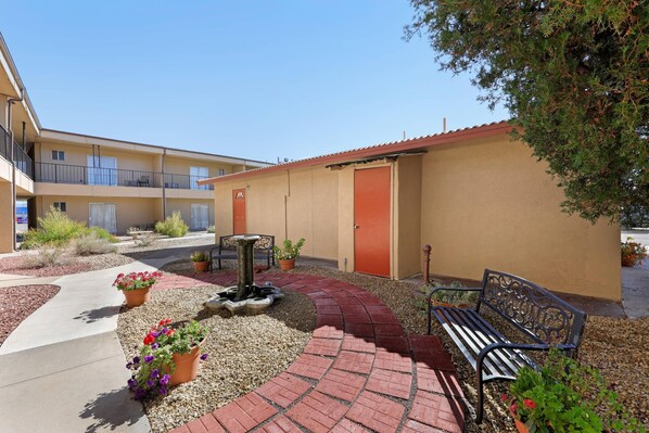 A courtyard with a bench, potted plants, and a water feature. - Econo Lodge Inn & Suites Socorro (Socorro)