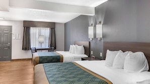 A hotel room with two beds, a desk, and a chair.