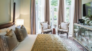 Une chambre d’hôtel avec un grand lit, deux fauteuils, une machine à café et une télévision.