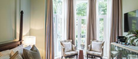 Ein Hotelzimmer mit einem großen Bett, zwei Sesseln, einer Kaffeemaschine und einem Fernseher.