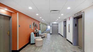A hotel corridor with orange walls, a herringbone-patterned floor, and a row of doors on the right. - Best Western Plus Chicagoland - Countryside (Countryside)