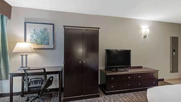 A hotel room with a desk, chair, television, wardrobe, and a bed.