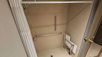 A small, enclosed shower area with a white shower curtain, a grab bar, and a handheld showerhead.