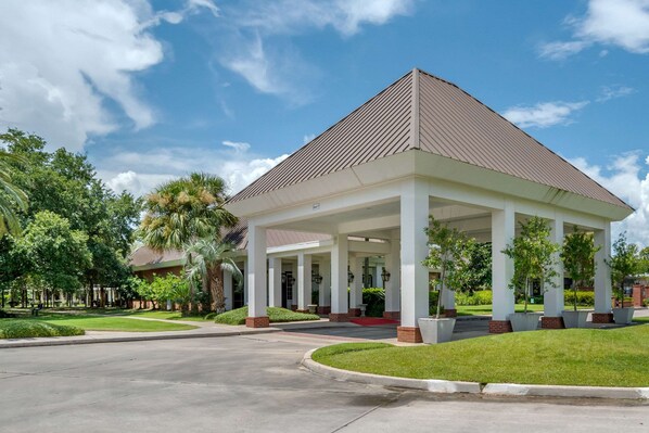 A covered pavilion with a tiled roof, surrounded by a well-maintained lawn and trees.
