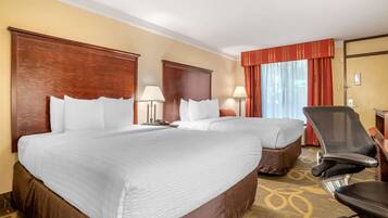 A hotel room with two beds, a desk, a chair, and a window with curtains.