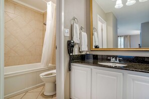 A bathroom with a bathtub, toilet, sink, and a large mirror.