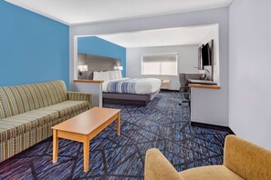 A hotel room with a sofa, a bed, a desk, and a chair.