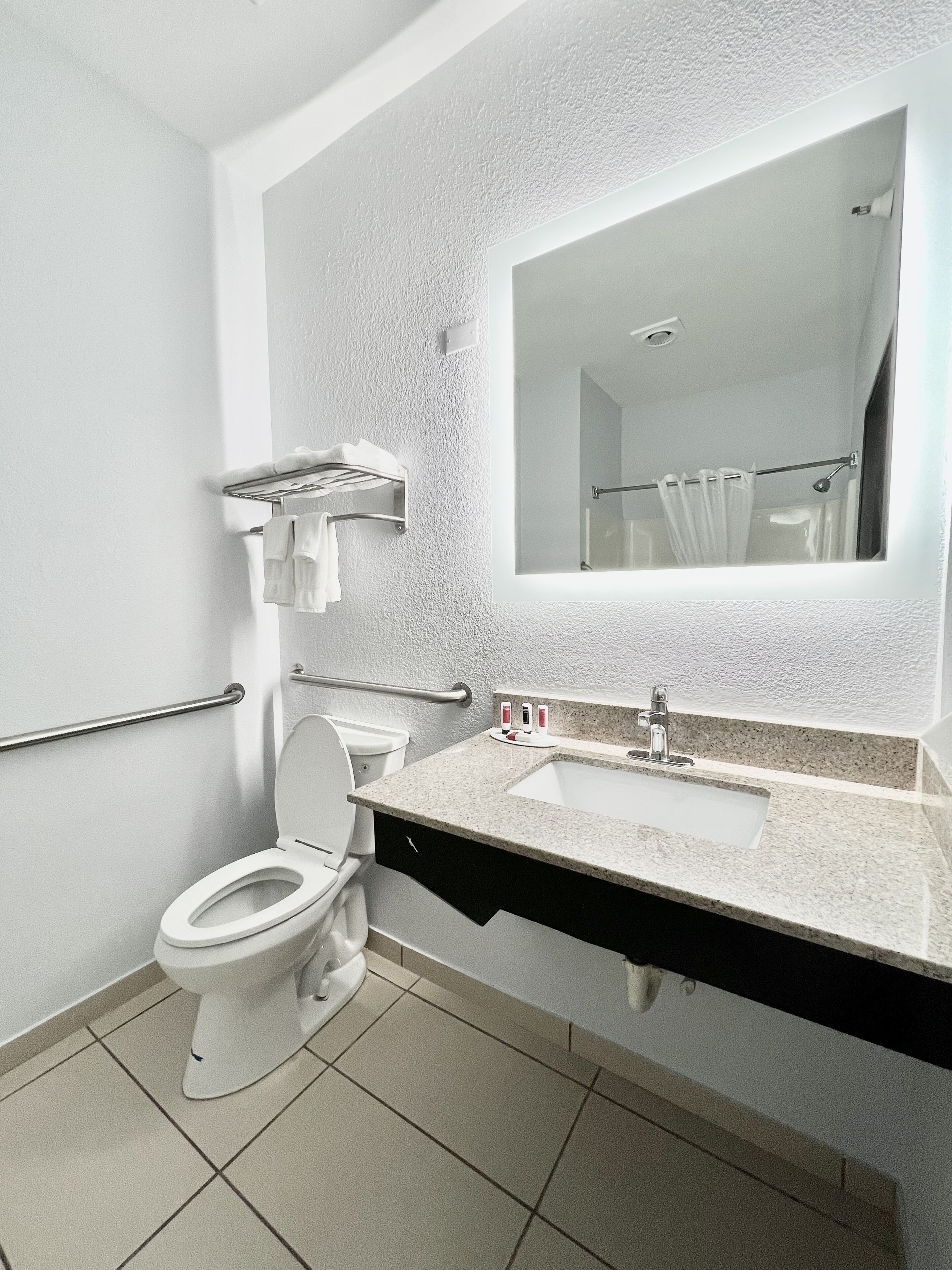 A modern bathroom with a toilet, sink, and mirror.