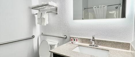 A modern bathroom with a toilet, sink, and mirror.