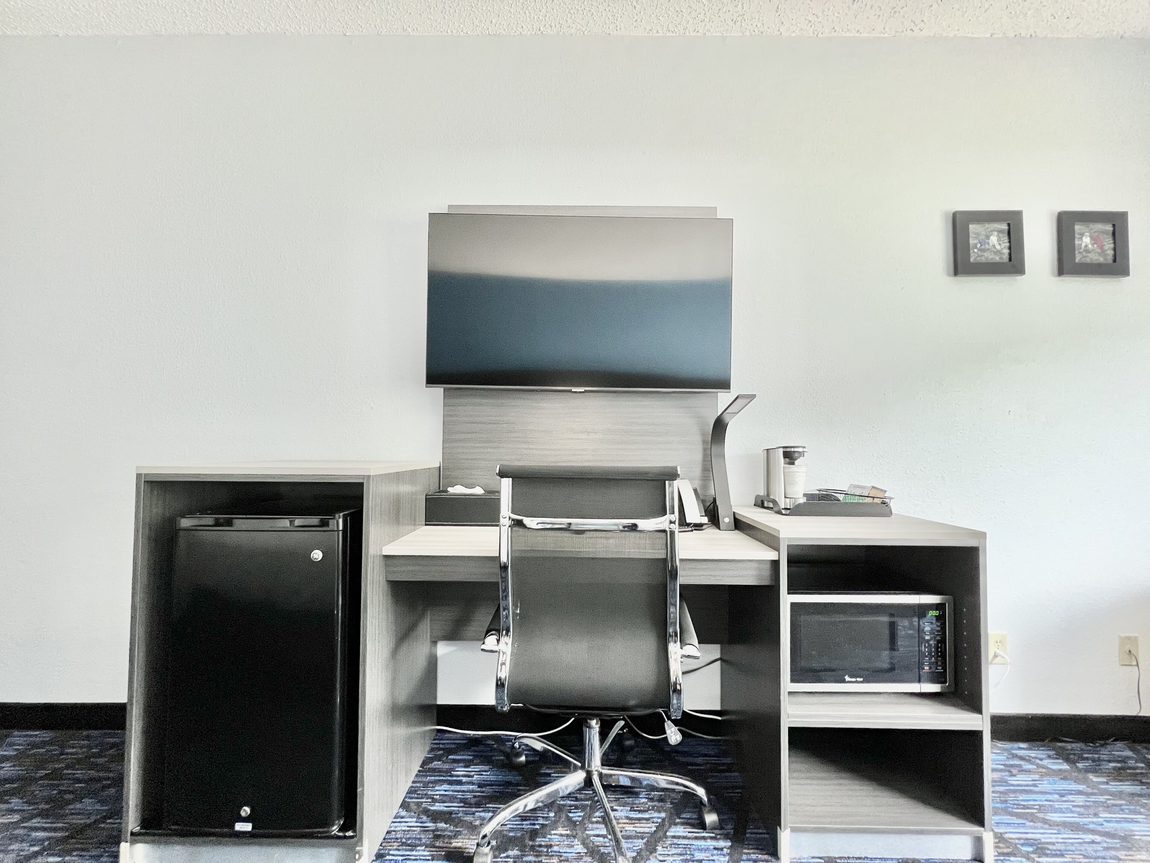 Una habitación de hotel compacta con escritorio, silla y microondas.