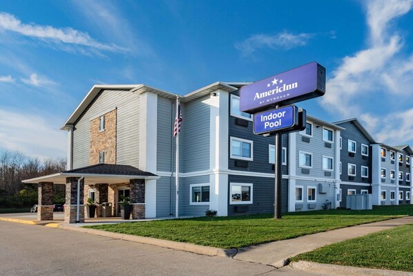 A modern hotel with a covered entrance, outdoor pool, and multiple floors.