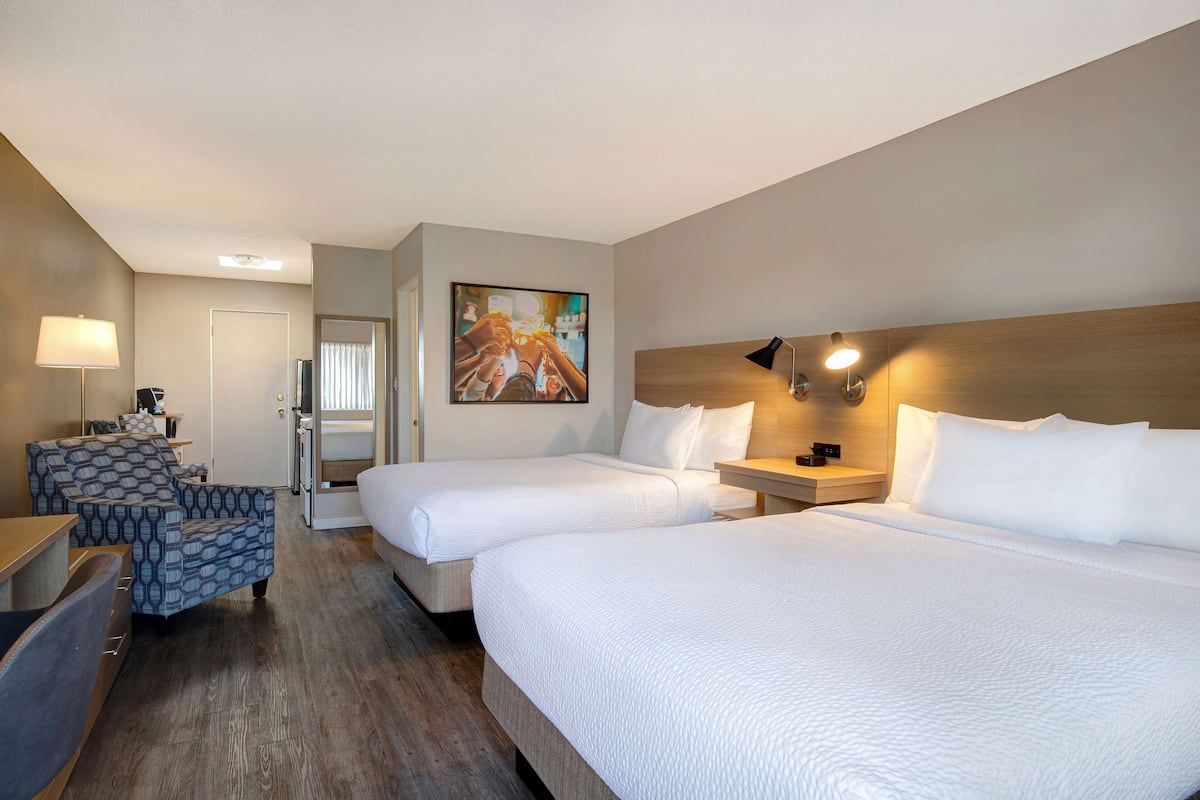 Ein Hotelzimmer mit zwei Betten, einem Sofa, einem Schreibtisch und einem Bild an der Wand.
