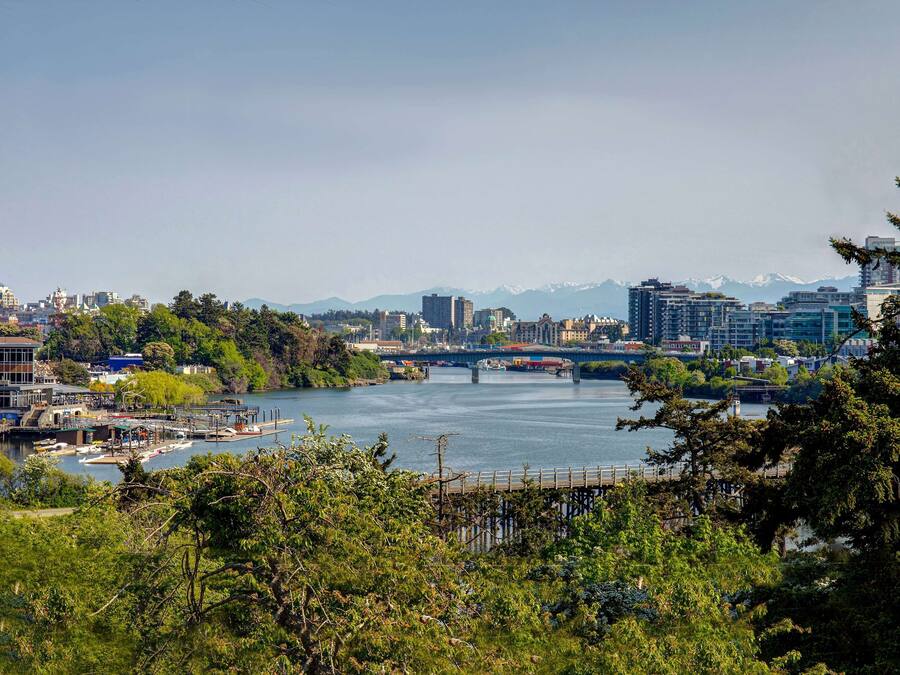 A river with a bridge, buildings, and mountains in the background.