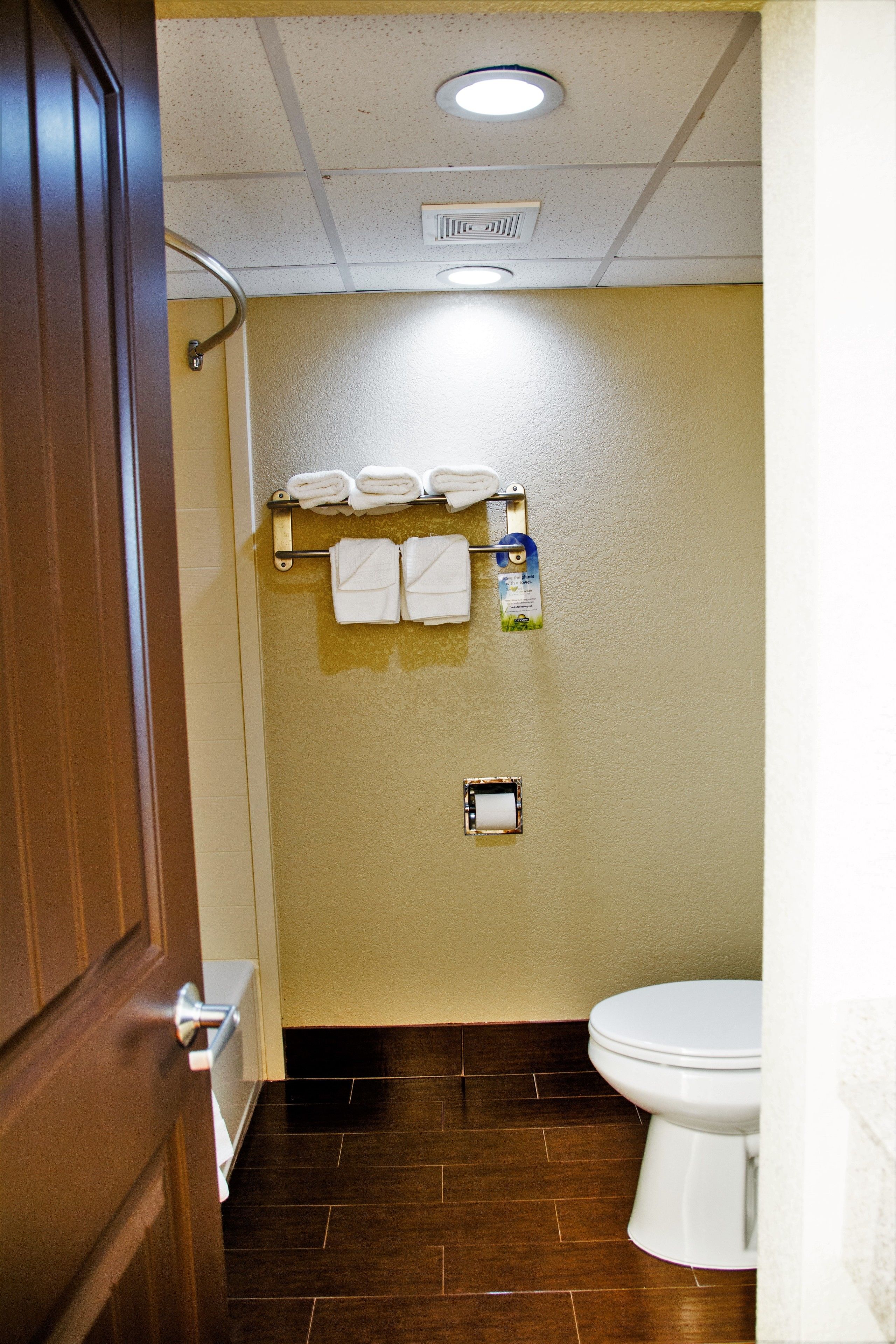 A bathroom with a toilet, a towel rack with towels, and a toilet paper holder.
