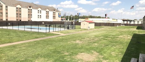 A hotel with a swimming pool, a fenced area, and a small shed.