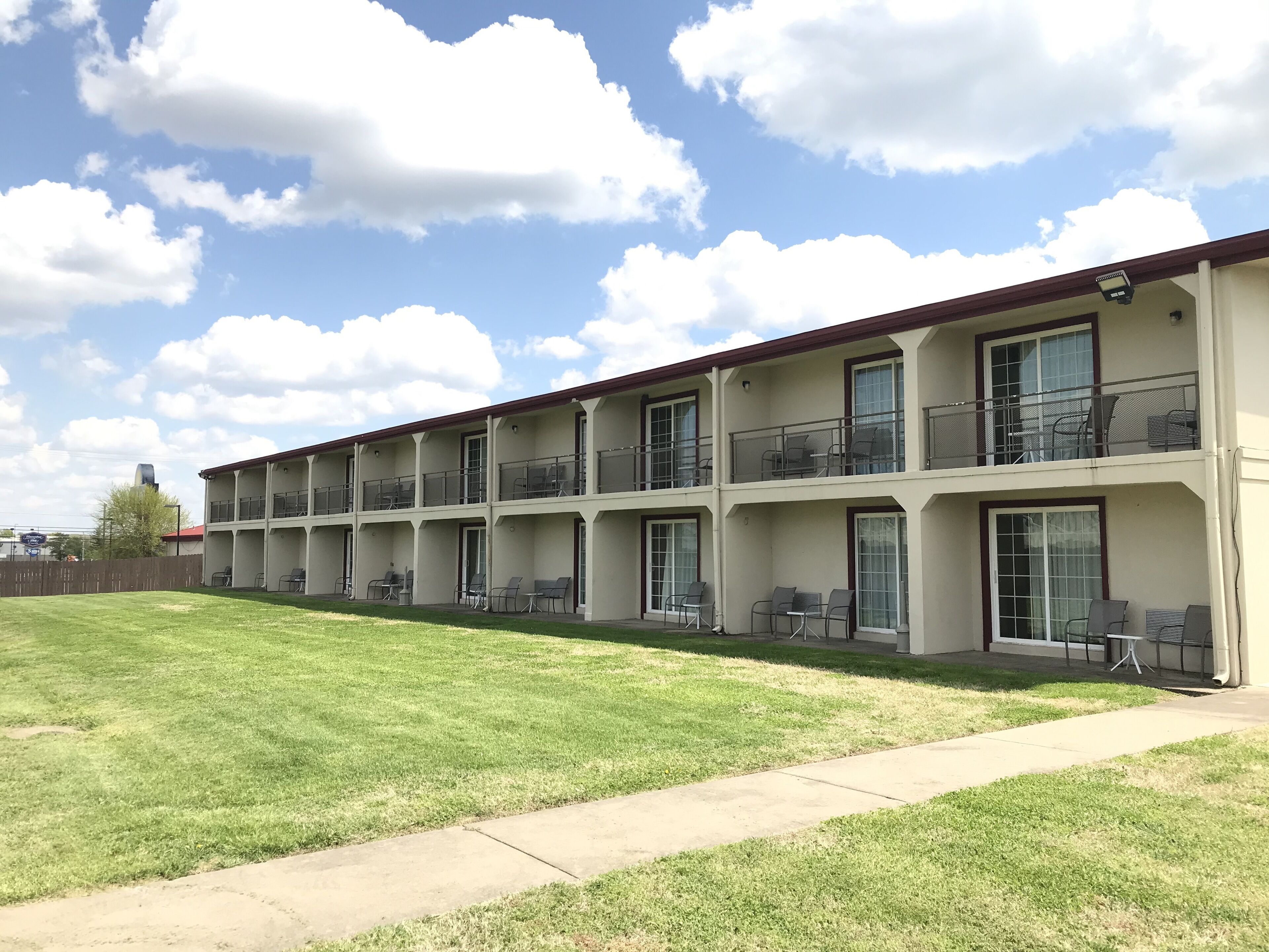 Ein mehrstöckiges Motel mit Balkonen, Außenbereich und einem gepflegten Rasen.