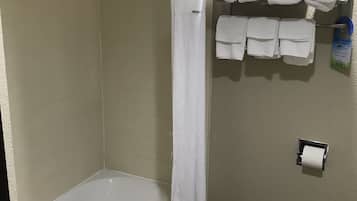 A bathroom with a bathtub, a shower curtain, a towel rack with towels, and a toilet paper holder.