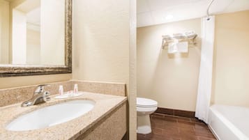 A bathroom with a sink, mirror, toilet, and bathtub.