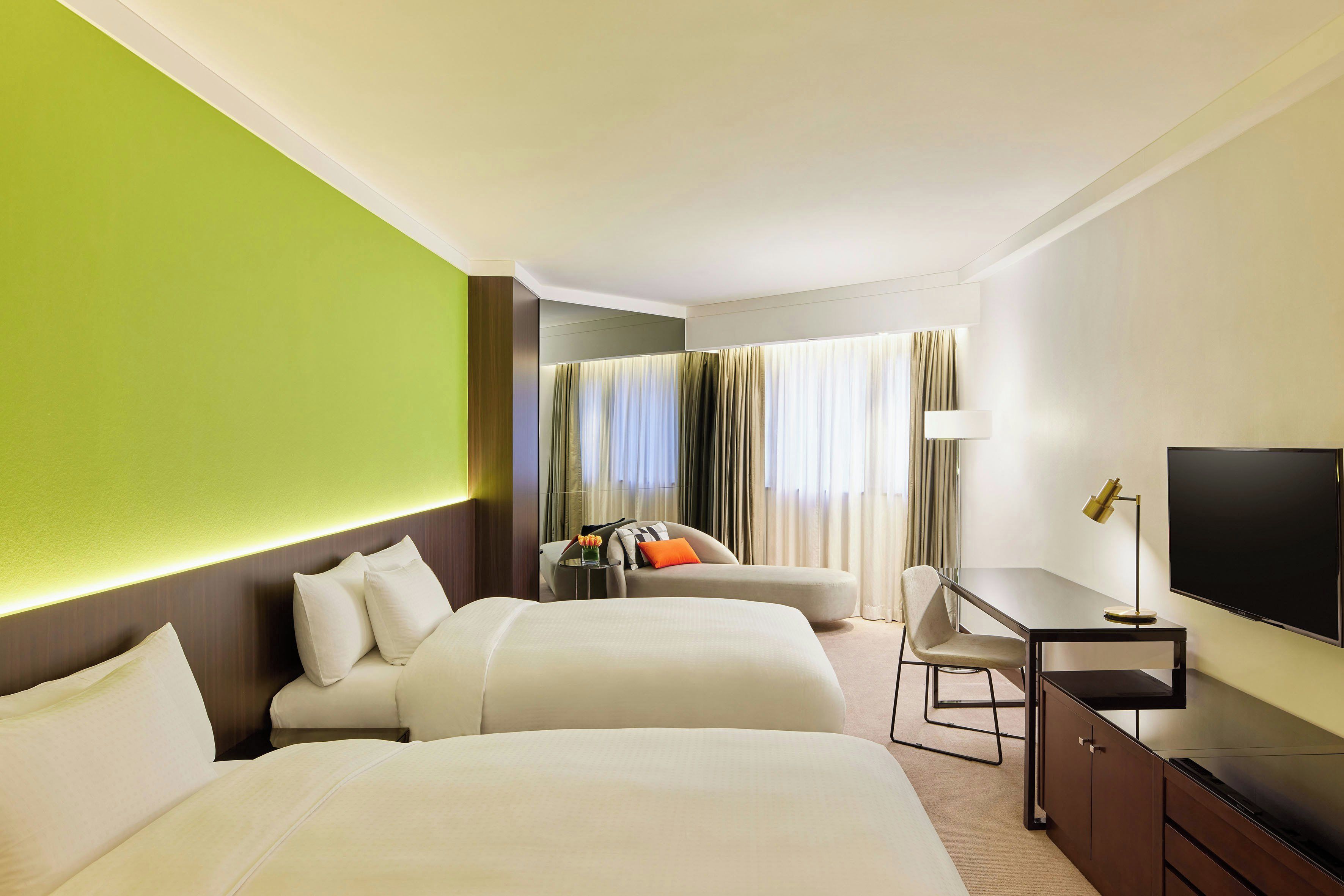Ein Hotelzimmer mit zwei Betten, einem Schreibtisch, einem Fernseher und Blick ins Freie.