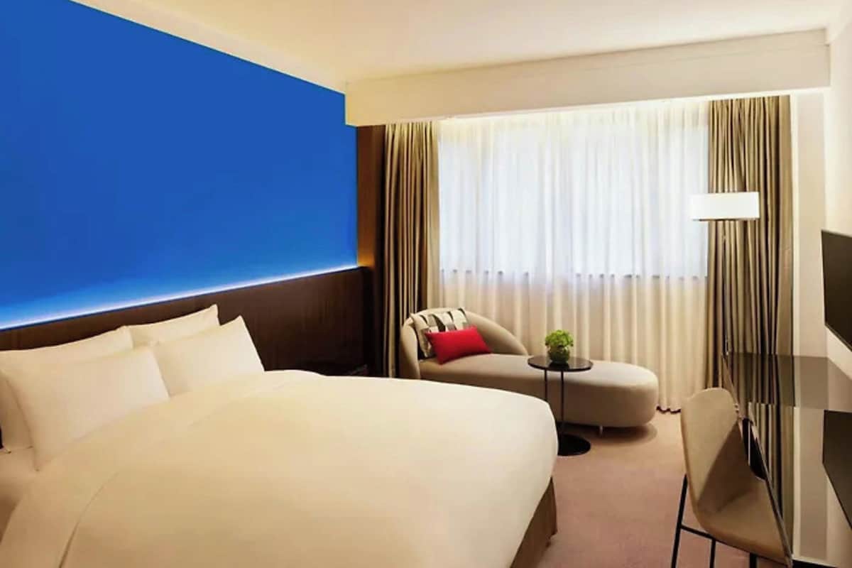 A hotel room with a large bed, a sofa, a chair, a small table, and a TV.