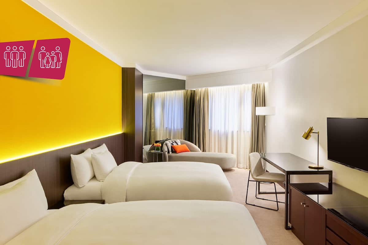 A hotel room with two beds, a desk, a TV, and a mirror.