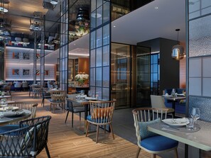 A modern restaurant interior with high ceilings, glass partitions, and contemporary furniture. - Prince, Marco Polo Hotel (Kowloon)