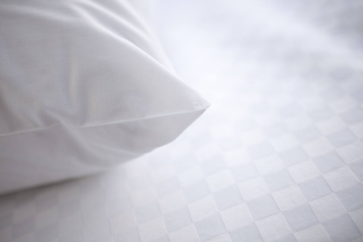A pillow on a bed with a checkered pattern.