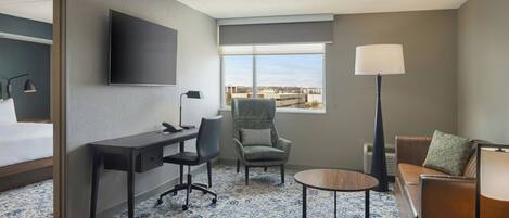 Une chambre d’hôtel avec un lit, un bureau, une chaise et une vue sur les bâtiments par la fenêtre.