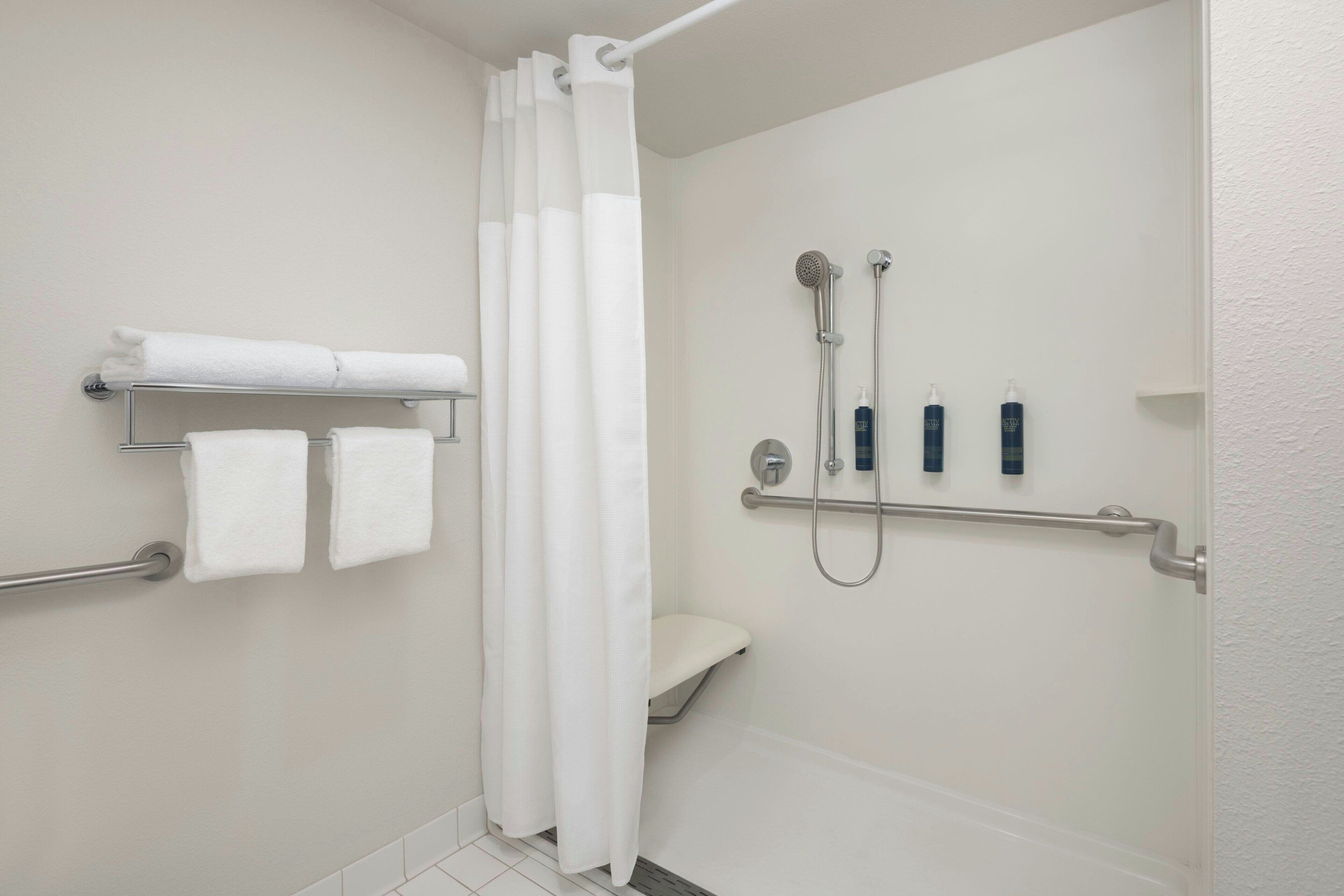 A bathroom with a shower, toilet, and towel rack.