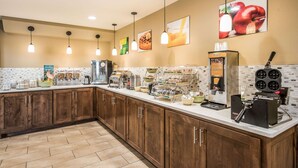 A kitchen with wooden cabinets, a coffee station, and a breakfast bar. - Quality Inn Arkadelphia - University Area (Caddo Valley)