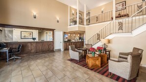 A spacious lobby with a reception desk, seating area, and a staircase leading to an upper level. - Quality Inn Arkadelphia - University Area (Caddo Valley)