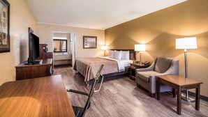 A hotel room with a bed, a desk, a chair, a TV, and two bedside lamps. - Quality Inn Arkadelphia - University Area (Caddo Valley)